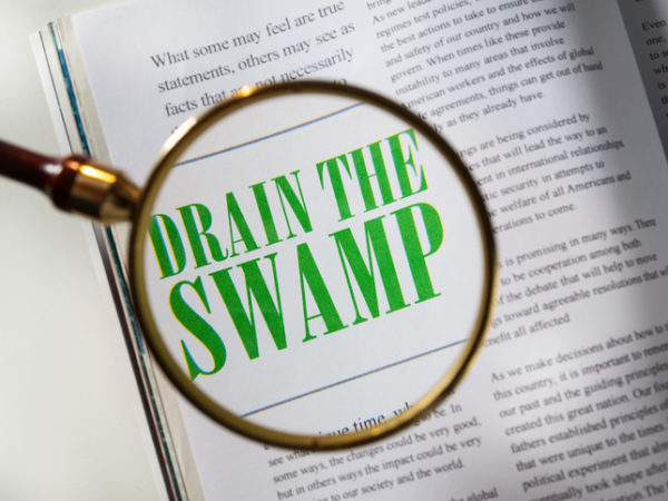 Magazine with article about Drain the Swamp with magnifying glass.